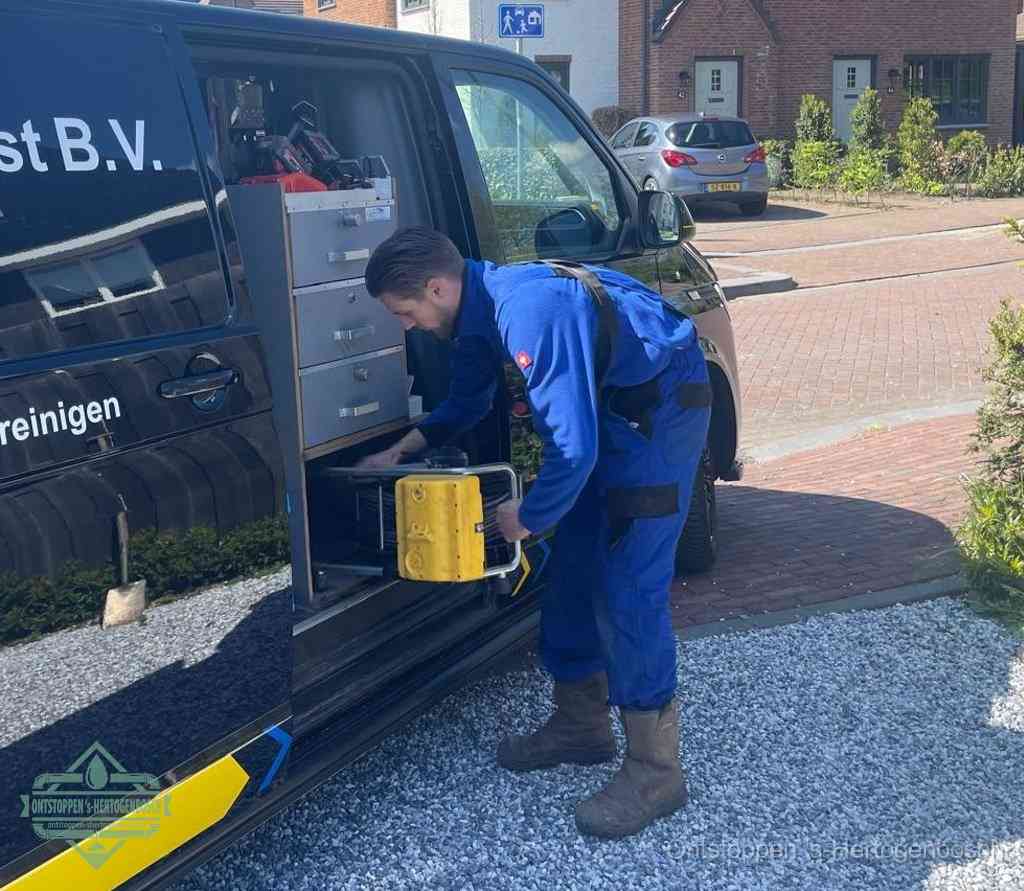 Een monteur pakt buiten op de oprit gereedschap uit de bedrijfsbus, het moment om een professional in te schakelen voor een verstopte afvoer in s-Hertogenbosch