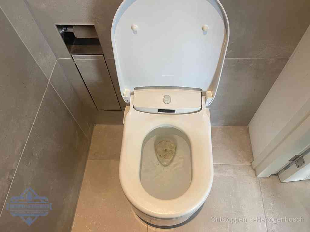 Een wit hangtoilet waarin een prop wc-papier op het water blijft drijven, een duidelijk signaal van een verstopte wc in s-Hertogenbosch