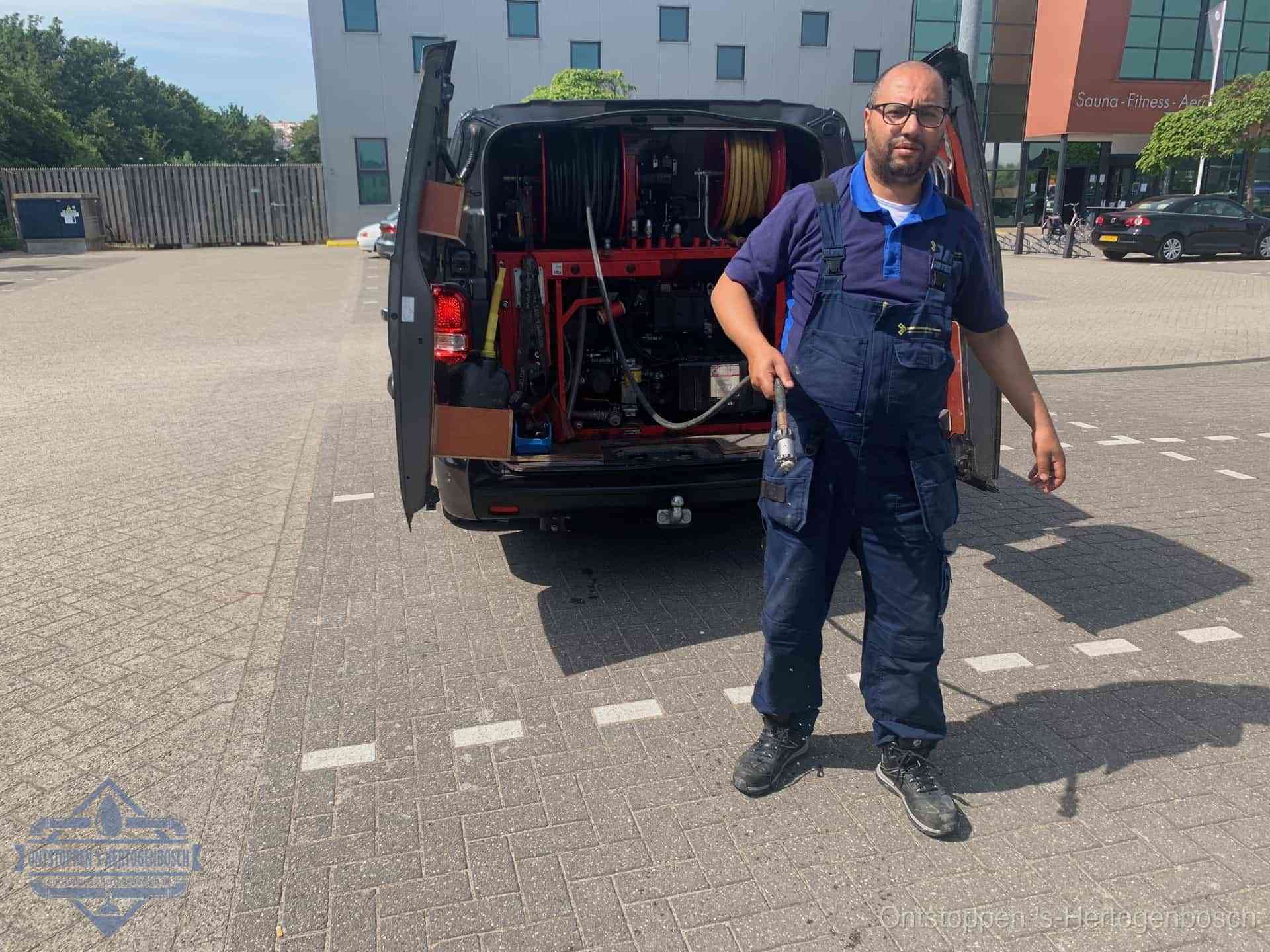 Een monteur bij zijn bestelbus met een hogedruk- en rioolreinigingsunit, klaar om de oorzaak van terugkerende wc-verstoppingen aan te pakken in s-Hertogenbosch