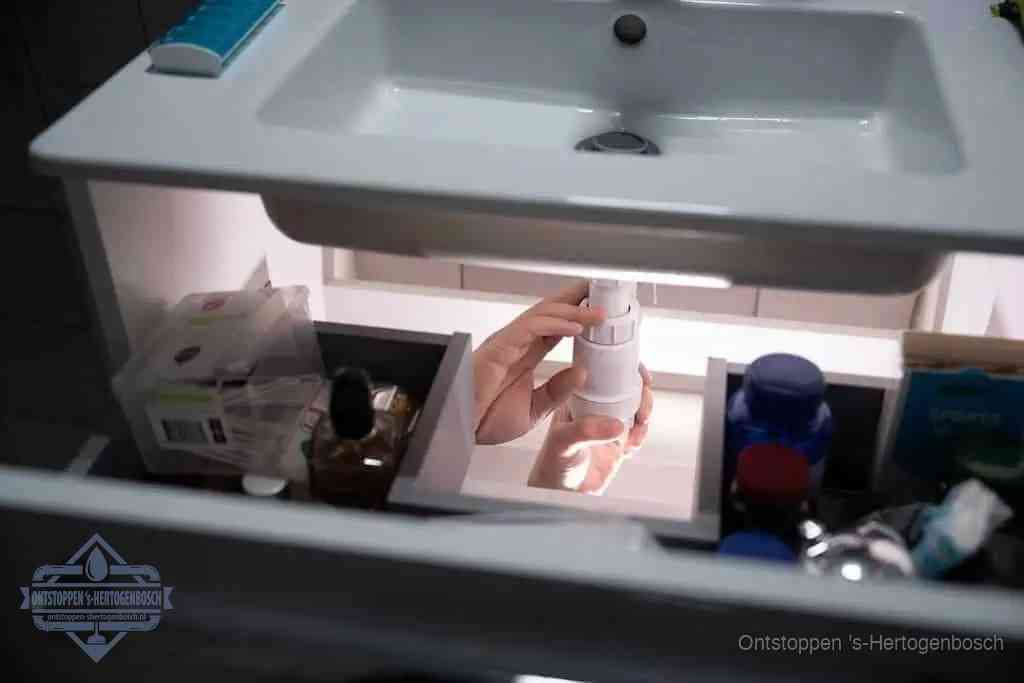 Een pompfles met zeep boven een wastafel in de toiletruimte, de warm water en afwasmiddel-methode om de wc te ontstoppen in s-Hertogenbosch