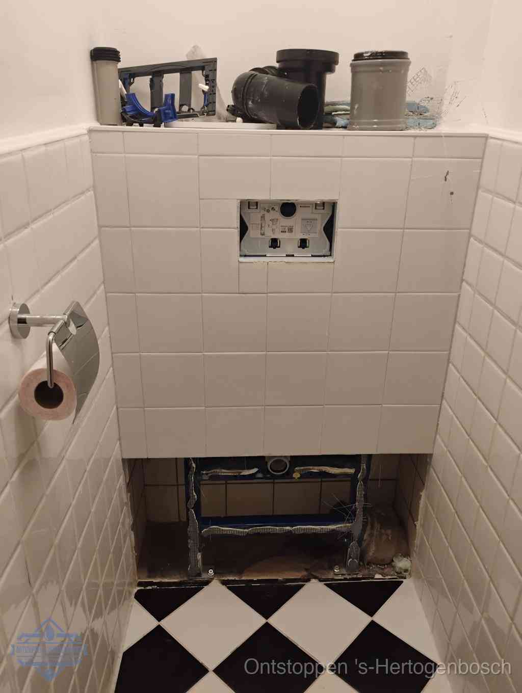 Een toiletruimte waar het hangtoilet en de inbouwreservoir-onderdelen zijn vrijgelegd voor onderhoud, periodiek nazicht voorkomt een wc-verstopping in s-Hertogenbosch
